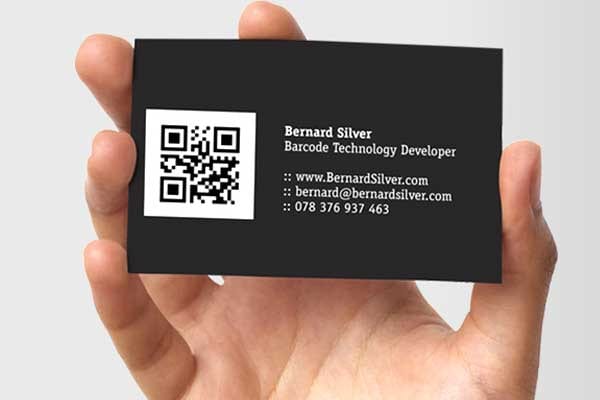 A hand holding a business card with a QR code on it