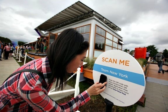 A visitor scanning a “Scan me” QR code sign at an outdoor event
